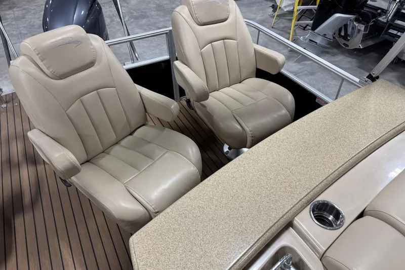 Slide: The Image of 2014 Bennington S 24 boat interior with beige captain chairs and wood-style flooring. - 10