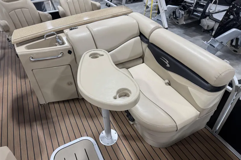 Slide: The Image of 2014 Bennington S 24 boat interior with beige seating and a small table. - 13