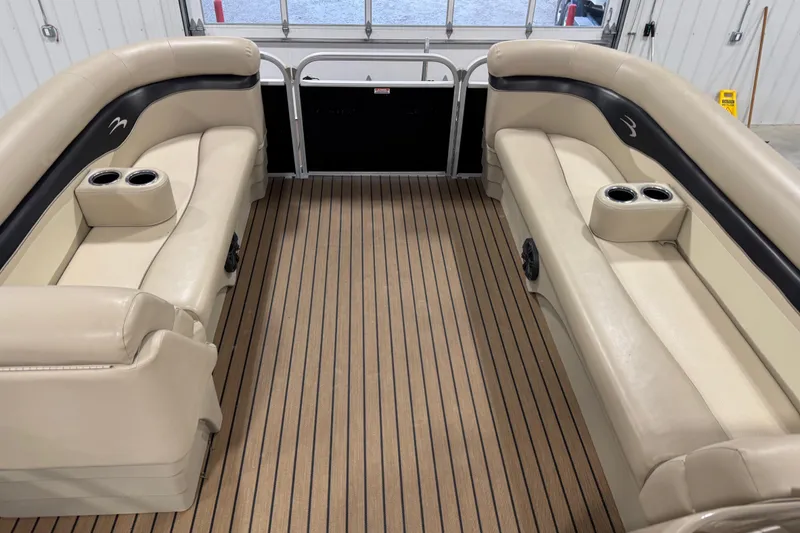 Slide: The Image of 2014 Bennington S 24 boat interior with beige seating and cup holders. - 14