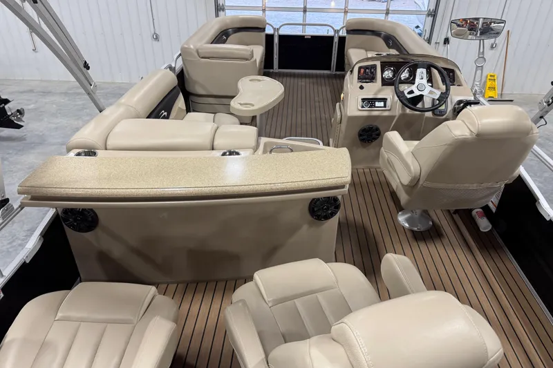 Slide: The Image of 2014 Bennington S 24 pontoon boat interior with beige seating and wood-style flooring. - 9