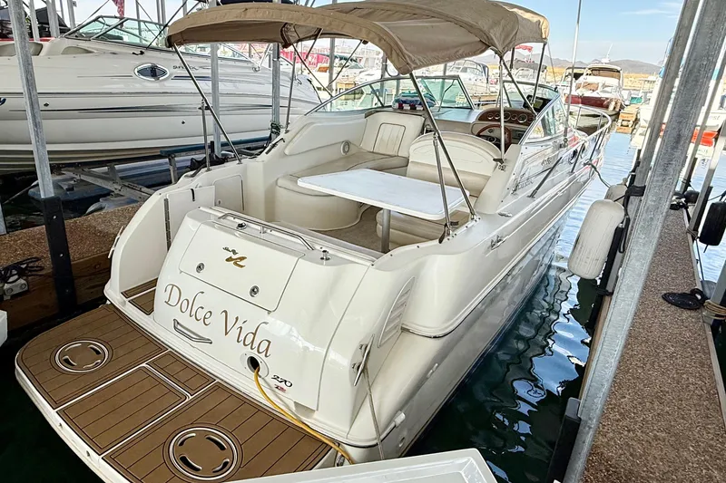 The Image of 2000 Sea Ray 270 Sundancer boat docked, featuring spacious seating and canopy. - 1