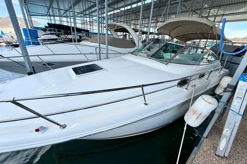Slide: The Image of 2000 Sea Ray 270 Sundancer docked in a marina, featuring sleek white design and covered cockpit. - 32