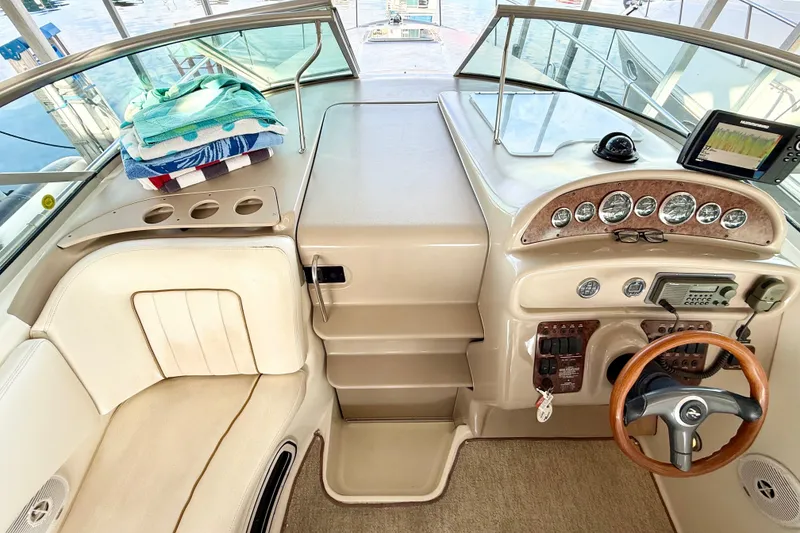 Slide: The Image of 2000 Sea Ray 270 Sundancer helm with gauges, steering wheel, and towels on seat. - 5