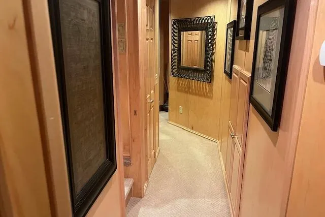 Slide: The Image of Narrow hallway in a 2008 Fantasy houseboat with framed artwork and wooden walls. - 24