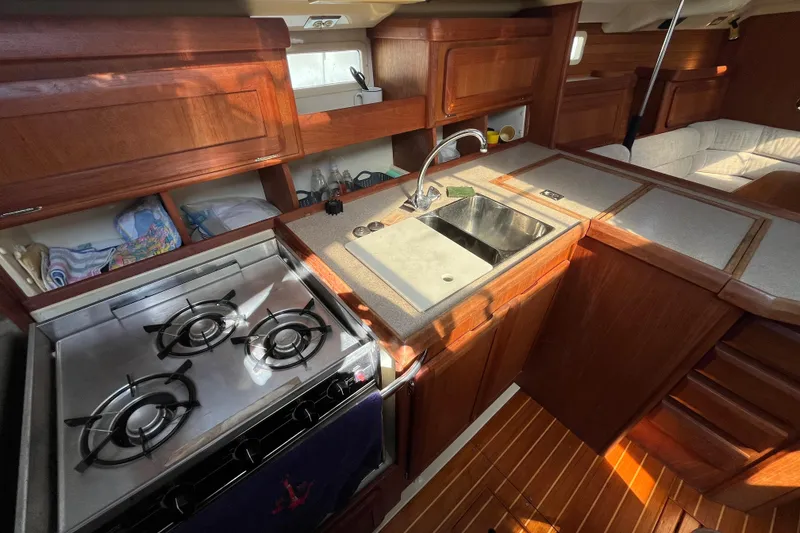 Slide: The Image of 1995 Hunter Legend 37.5 yacht interior kitchen with stove, sink, and wooden cabinetry. - 13