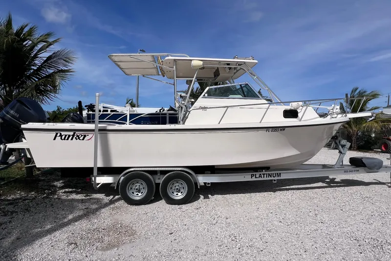 Slide: The Image of 2005 Parker 2510 Walkaround boat on trailer, parked outdoors under blue sky. - 11