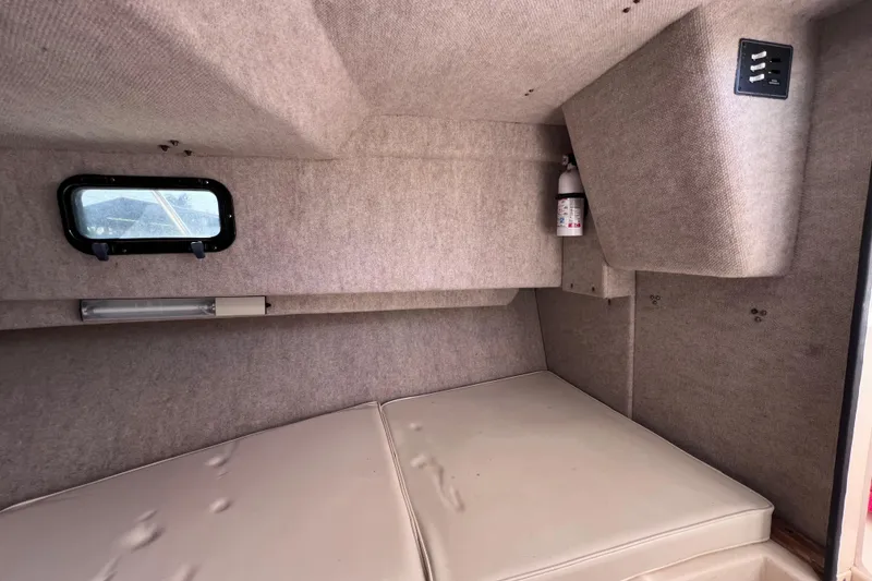 Slide: The Image of 2005 Parker 2510 Walkaround cabin interior with window, fire extinguisher, and cushioned seating. - 49
