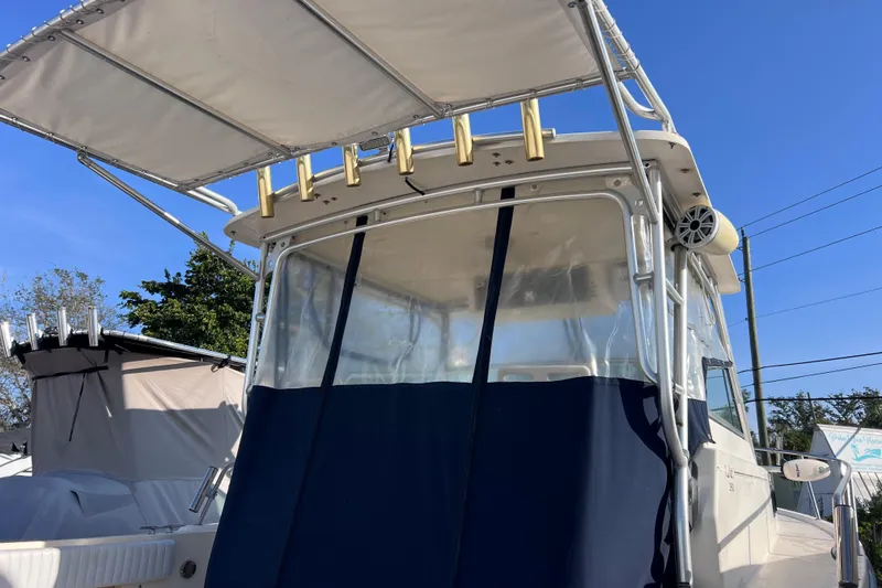 Slide: The Image of 2005 Parker 2510 Walkaround boat with canopy and rod holders, docked under clear blue sky. - 56