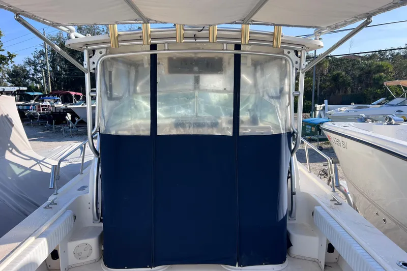 Slide: The Image of 2005 Parker 2510 Walkaround boat with blue canvas enclosure, docked in a marina. - 58