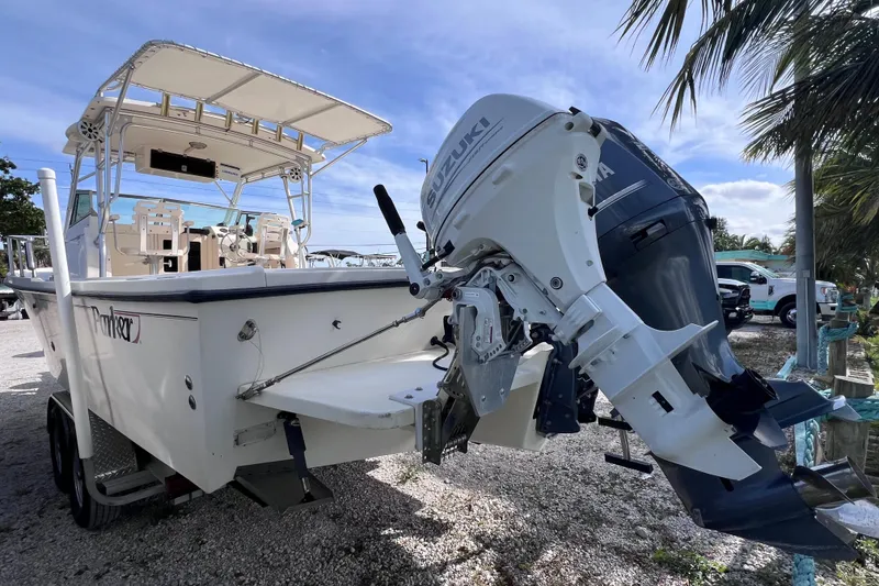 Slide: The Image of 2005 Parker 2510 Walkaround boat with Suzuki outboard motor, parked near palm trees. - 9