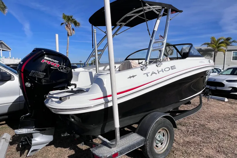 Slide: The Image of 2019 Tahoe 450 TS boat with Mercury Pro XS engine on trailer, parked near palm trees. - 0