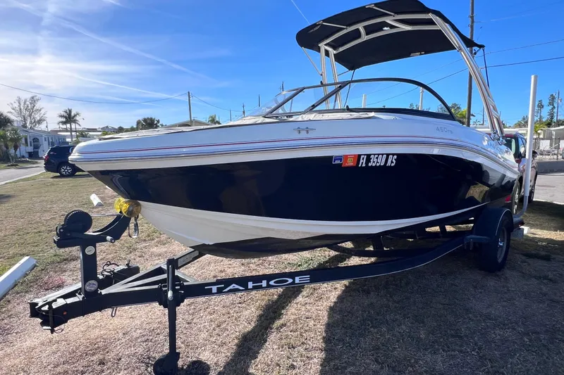 Slide: The Image of 2019 Tahoe 450 TS boat on trailer, parked outdoors under clear blue sky. - 2