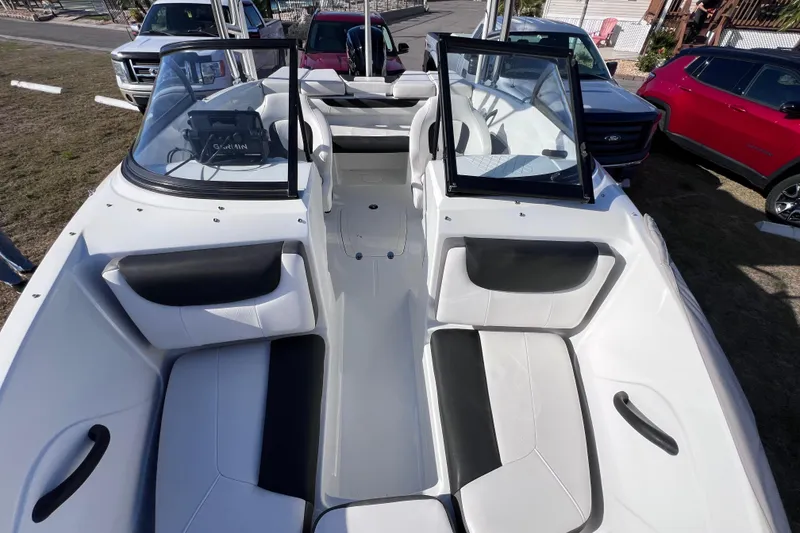 Slide: The Image of 2019 Tahoe 450 TS boat interior with black and white seating, parked near vehicles. - 24