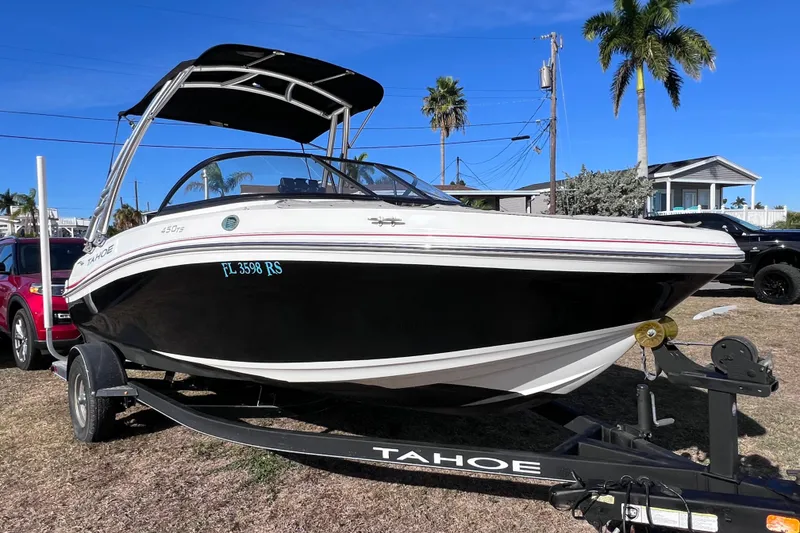 Slide: The Image of 2019 Tahoe 450 TS boat on trailer, parked outdoors under clear blue sky. - 4
