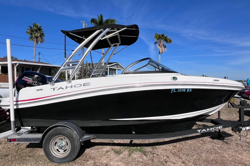 Slide: The Image of 2019 Tahoe 450 TS boat on trailer, parked outdoors under clear blue sky. - 6
