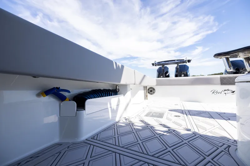 Slide: The Image of 2023 Freeman 47 boat deck with hose storage and dual engines under a clear sky. - 101