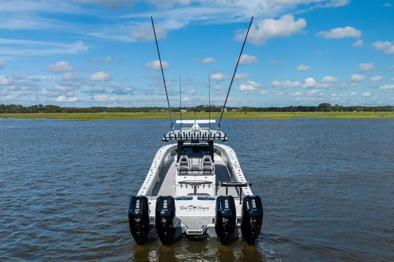 Slide: The Image of 2023 Freeman 47 boat with quad 400 engines on a calm lake under blue skies. - 12