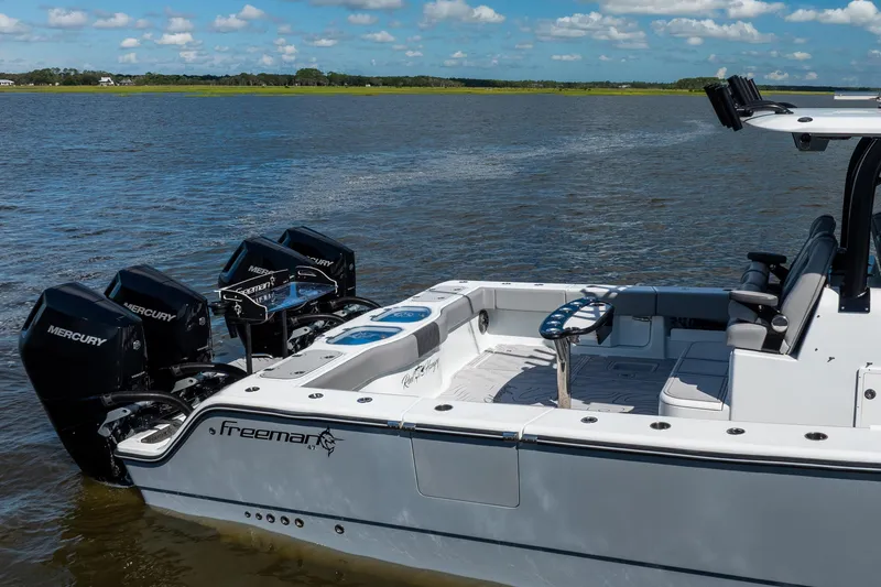 Slide: The Image of 2023 Freeman 47 boat with Mercury engines on a calm lake under a blue sky. - 14