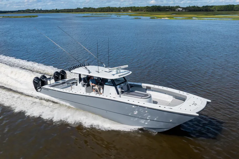 Slide: The Image of 2023 Freeman 47 boat cruising on a serene lake with lush green shoreline. - 25