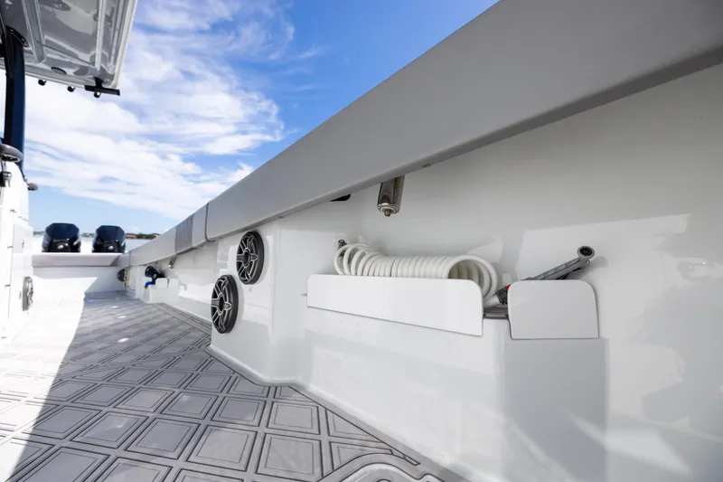 Slide: The Image of 2023 Freeman 47 boat deck with speakers and coiled hose under a clear blue sky. - 99
