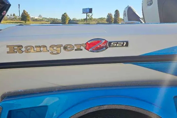 Slide: The Image of 2026 Ranger Z521 boat with blue and white design, parked outdoors. - 2