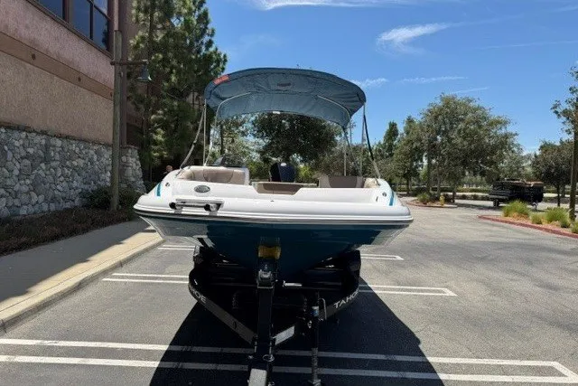 Slide: The Image of 2026 Tahoe 1950 boat with canopy parked in sunny outdoor setting. - 2