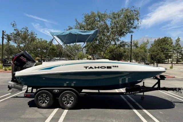 Slide: The Image of 2026 Tahoe 1950 boat on trailer in sunny parking lot with trees and blue sky. - 1