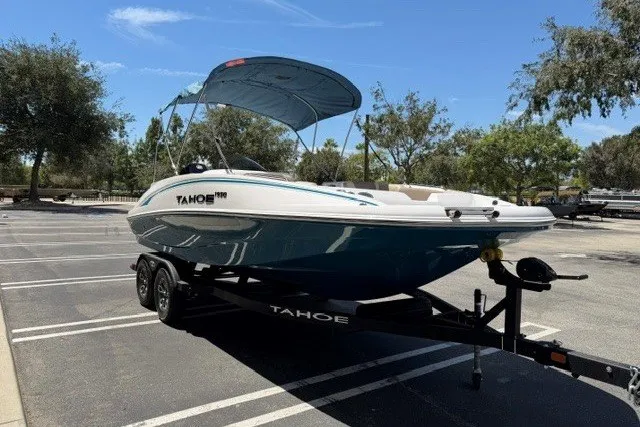 Slide: The Image of 2026 Tahoe 1950 boat on trailer in parking lot, under clear blue sky. - 4