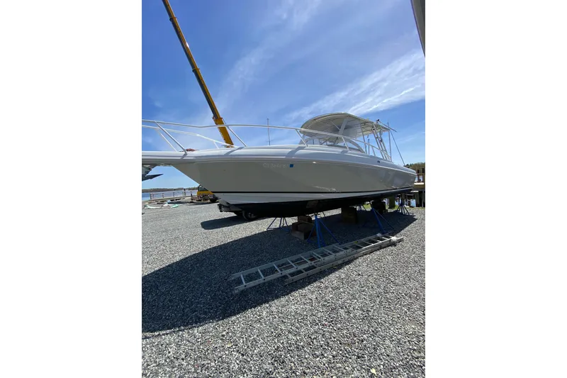 Slide: The Image of 1996 Intrepid 337 boat on stands, under clear blue sky, with crane in background. - 3
