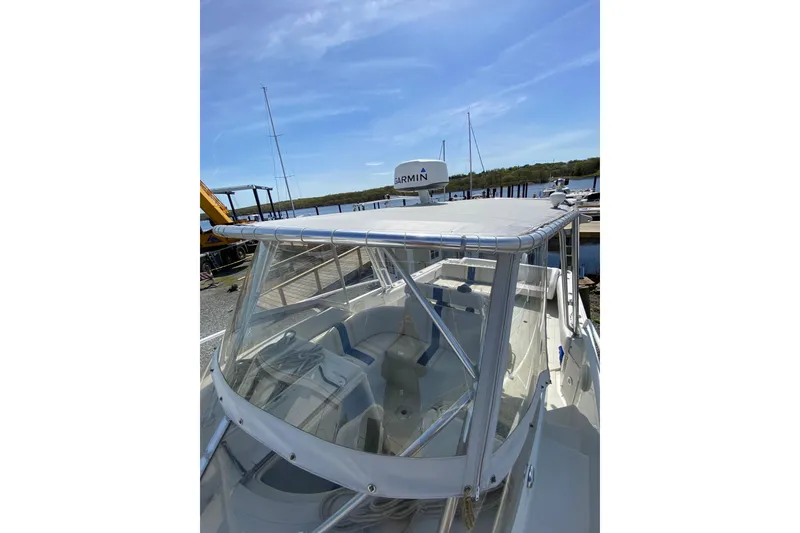 Slide: The Image of 1996 Intrepid 337 boat with canopy, docked near water under clear blue sky. - 31