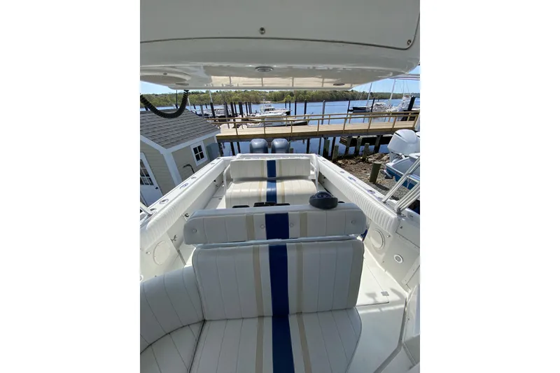 Slide: The Image of 1996 Intrepid 337 boat interior with striped seating, docked by a scenic waterfront. - 35