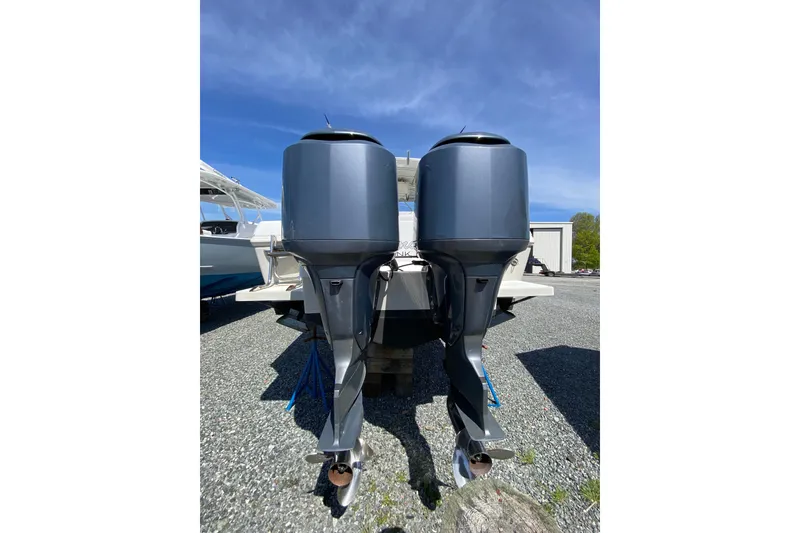 Slide: The Image of 1996 Intrepid 337 boat with dual outboard motors, parked on gravel under clear blue sky. - 40