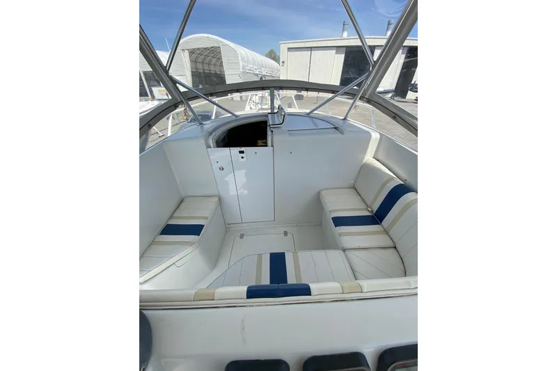Slide: The Image of 1996 Intrepid 337 boat interior with white and blue seating, docked near storage buildings. - 43