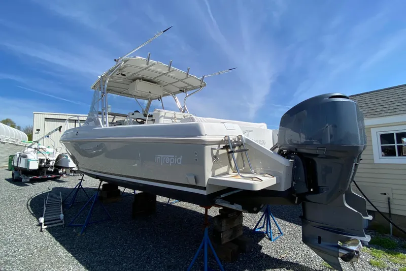 Slide: The Image of 1996 Intrepid 337 boat on stands, with outboard motor, under clear blue sky. - 8