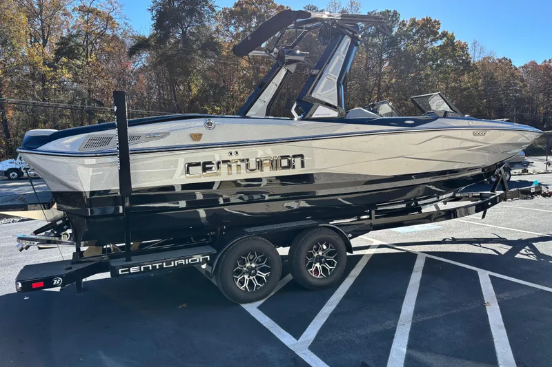 Slide: The Image of 2026 Centurion Nv243 boat on trailer, parked outdoors, surrounded by trees. - 4