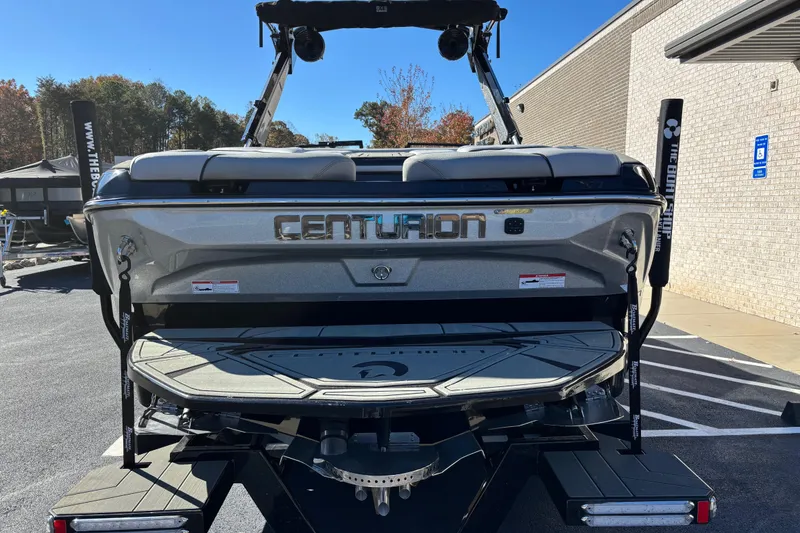 Slide: The Image of 2026 Centurion Nv243 boat rear view in parking lot, showcasing sleek design and branding. - 5