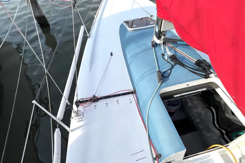 Slide: The Image of 2015 Wraceboats GP26 sailboat with red sail, docked on calm water. - 12