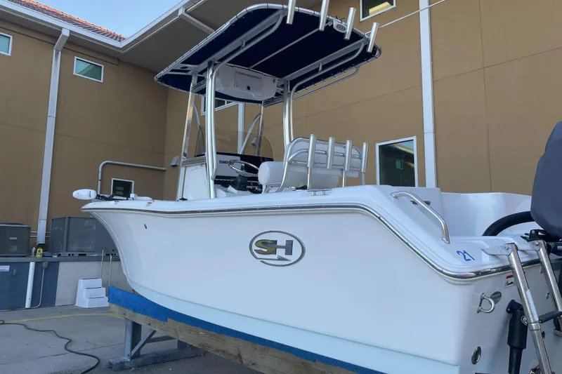 Slide: The Image of 2017 Sea Hunt Triton 210 boat with T-top, docked near a building. - 2