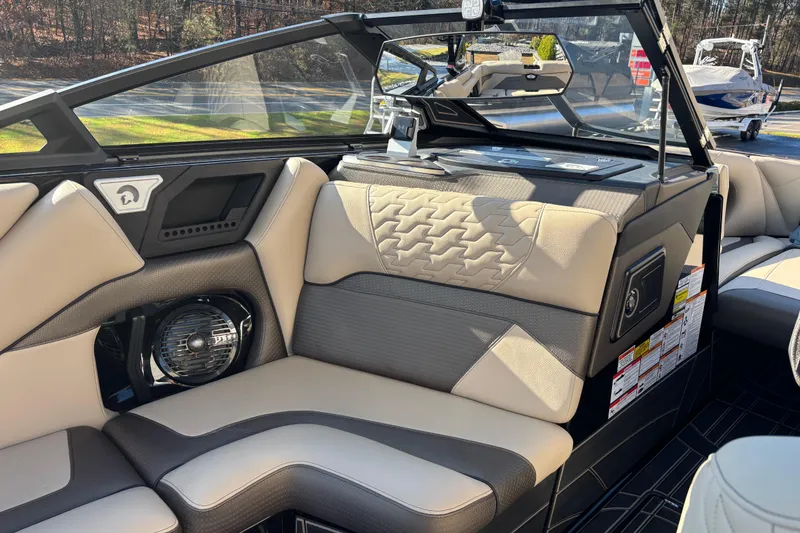 Slide: The Image of 2026 Centurion Ri245 boat interior with beige and gray seating, modern design, and speaker system. - 12