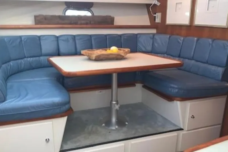 Slide: The Image of 1994 Carver 440 Aft Cabin Motor Yacht interior with blue cushioned seating and dining table. - 6