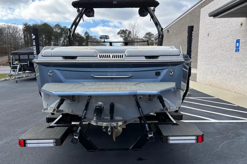 Slide: The Image of 2026 Supreme S220 boat rear view, showcasing swim platform and propeller, parked outdoors. - 3