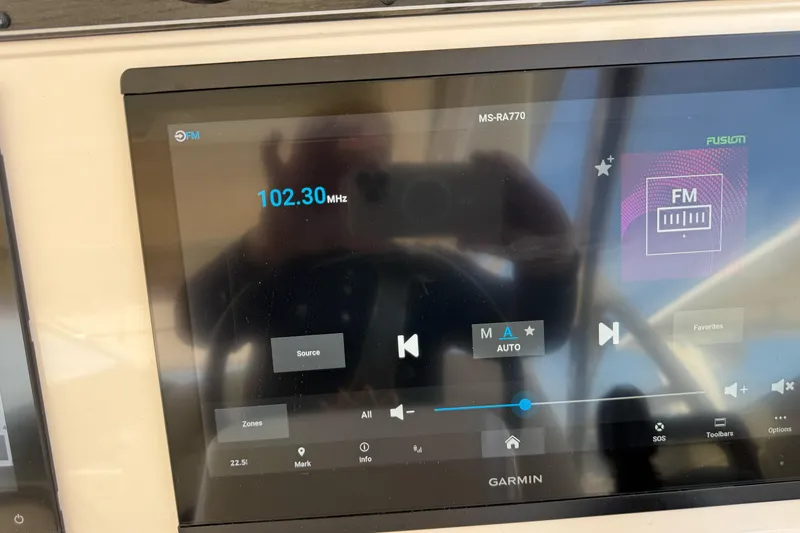Slide: The Image of Garmin display on 2023 Grady-White Freedom 335 showing FM radio at 102.30 MHz. - 16