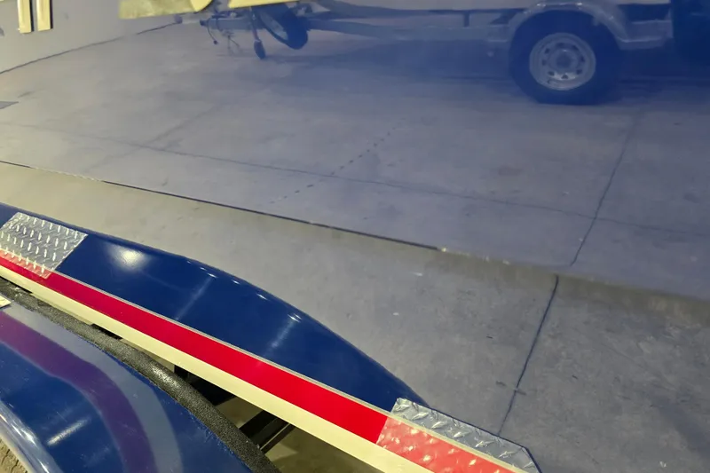 Slide: The Image of Shiny blue Larson All American 23 boat trailer, 2014 model, with red stripe detail. - 14