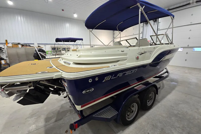 Slide: The Image of 2014 Larson All American 23 boat with blue hull and canopy in a garage. - 16