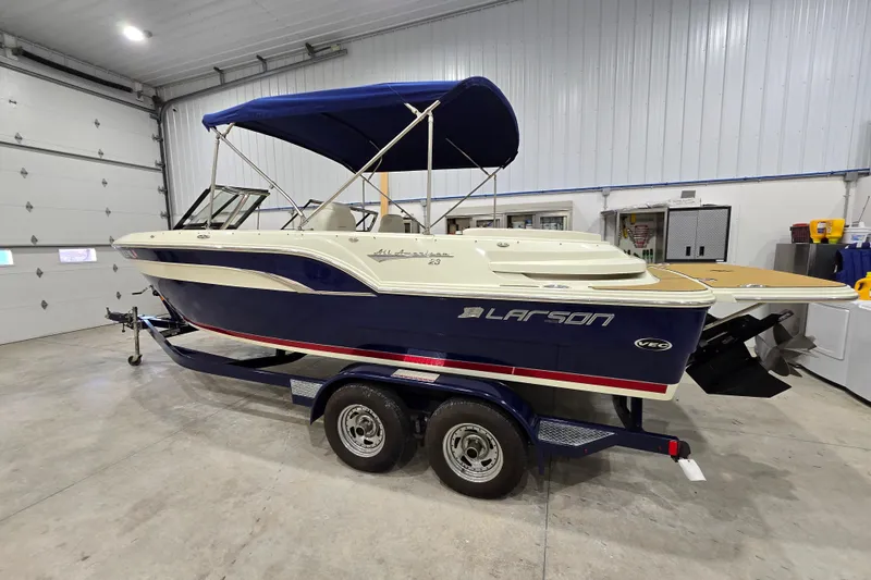 Slide: The Image of 2014 Larson All American 23 boat with blue canopy in a garage setting. - 25