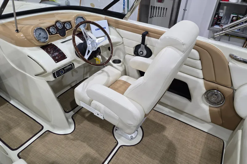 Slide: The Image of 2014 Larson All American 23 boat interior with beige and white seating, steering wheel, and dashboard. - 45