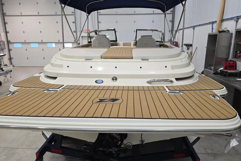 Slide: The Image of 2014 Larson All American 23 boat in a garage, showcasing its sleek design and spacious deck. - 53