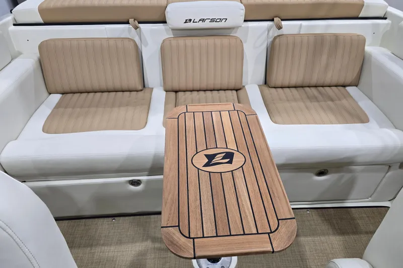 Slide: The Image of 2014 Larson All American 23 boat interior with beige seating and wooden table. - 56