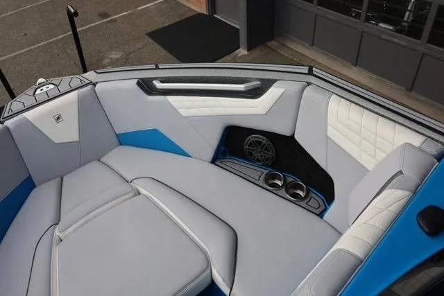 Slide: The Image of 2022 Nautique Super Air Nautique S23 interior with blue and gray seating, cup holders, and speaker. - 27
