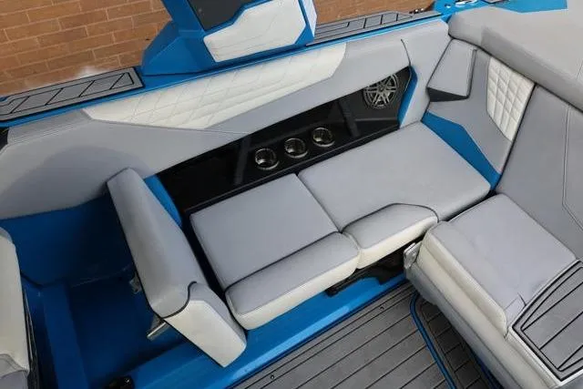 Slide: The Image of 2022 Nautique Super Air Nautique S23 interior with blue and gray seating, cup holders, and speaker. - 34